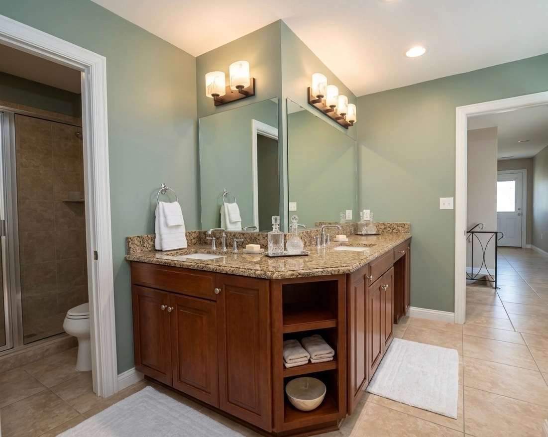 Remodeled primary bathroom with custom tile and granite countertops